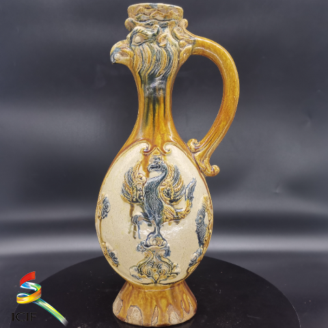 唐三彩凤首壶  展品介绍：壶体似凤，颈塑凤首，尖啄凸眼，凤冠高耸，凤口衔珠，象征壶流；腹呈椭圆，两面浮雕，分饰麒麟送子图、凤凰展翅图；壶足呈喇叭形，遍身施黄、绿、白、蓝等釉。造型巧妙，是波斯萨珊式器物风格的代表同时体现了唐代丰满健实的艺术特色，这种把外来文化和传统民族艺术结合的装饰手法，是唐三彩造型上的创新。.png